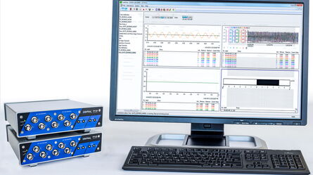 A computer monitor displays data analysis software alongside two stacked blue VibPilot devices on a desk.