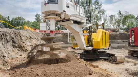 A large construction drill bores into the ground, creating rotational and torsional vibrations in the excavation site.
