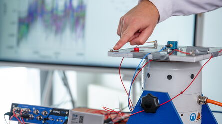 A person demonstrates a scientific experiment using electronic equipment and sensors in a laboratory setting.