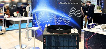 A bustling trade show booth showcases data acquisition technology with vibrant graphics and interactive displays.