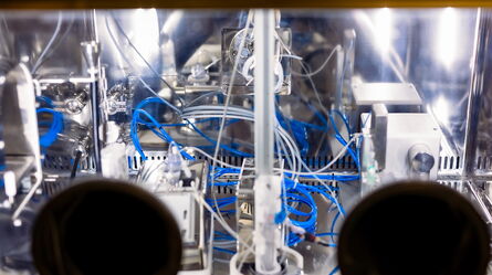 A complex system of blue wires and metallic components is integrated within a climate-controlled monitoring chamber.