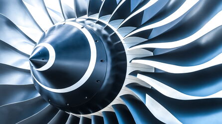 Close-up of a sleek turbomachinery engine fan with metal blades showcasing custom excitation solutions.