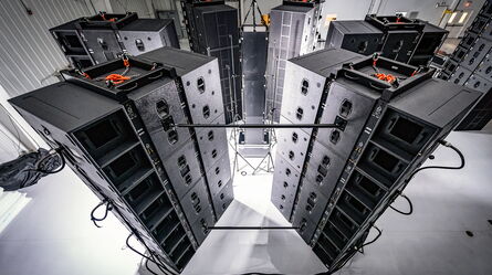 A series of large speakers are arranged in a circle for acoustic testing in a spacious indoor environment.