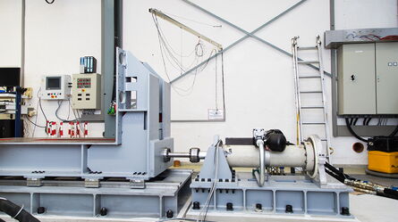 A servohydraulic system is set up in an industrial lab with control panels and machinery for advanced testing.
