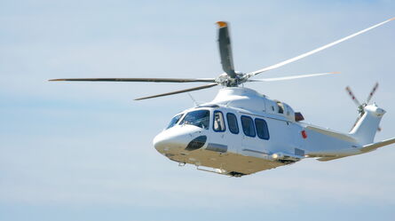A white helicopter is flying against a clear blue sky, showcasing advanced control for rotorcraft testing.