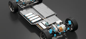 An electric vehicle chassis with visible battery packs and motors is displayed on a glossy gray surface.