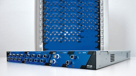 An m+p VibRunner DAQ module and a rack stacked with several modules s displayed on a white surface.