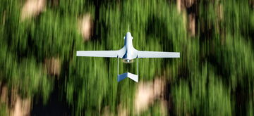 A white drone flies over a blurred green forest, creating a dynamic aerial view reminiscent of space travel.