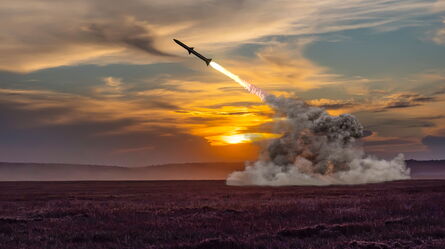 A missile launches dramatically against a vibrant sunset sky, leaving a trail of smoke and fire, reflecting combat-relevant dynamics.