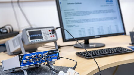 A calibration setup with a signal generator is connected to a computer displaying a calibration certificate on the screen.