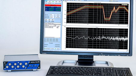 A computer monitor displays vibration control data next to a VibPilot device and keyboard.