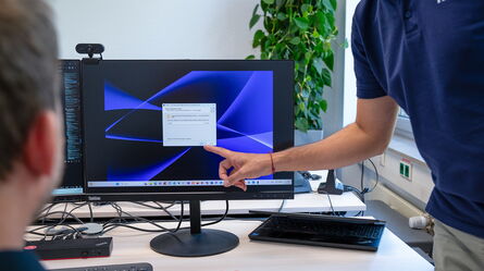 A person points at a computer screen displaying a license activation window in an office setting.