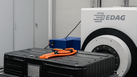 A battery is undergoing a safety test in a lab, connected by orange cables to advanced testing equipment.