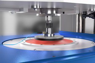 A close-up of a mechanical press machine operating on a circular metal component with precision in an industrial setting.