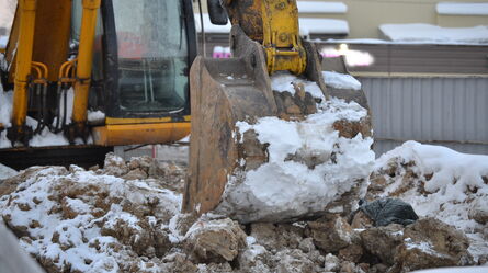 An excavator digs through snow-covered earth, highlighting combined environmental and vibration testing challenges.